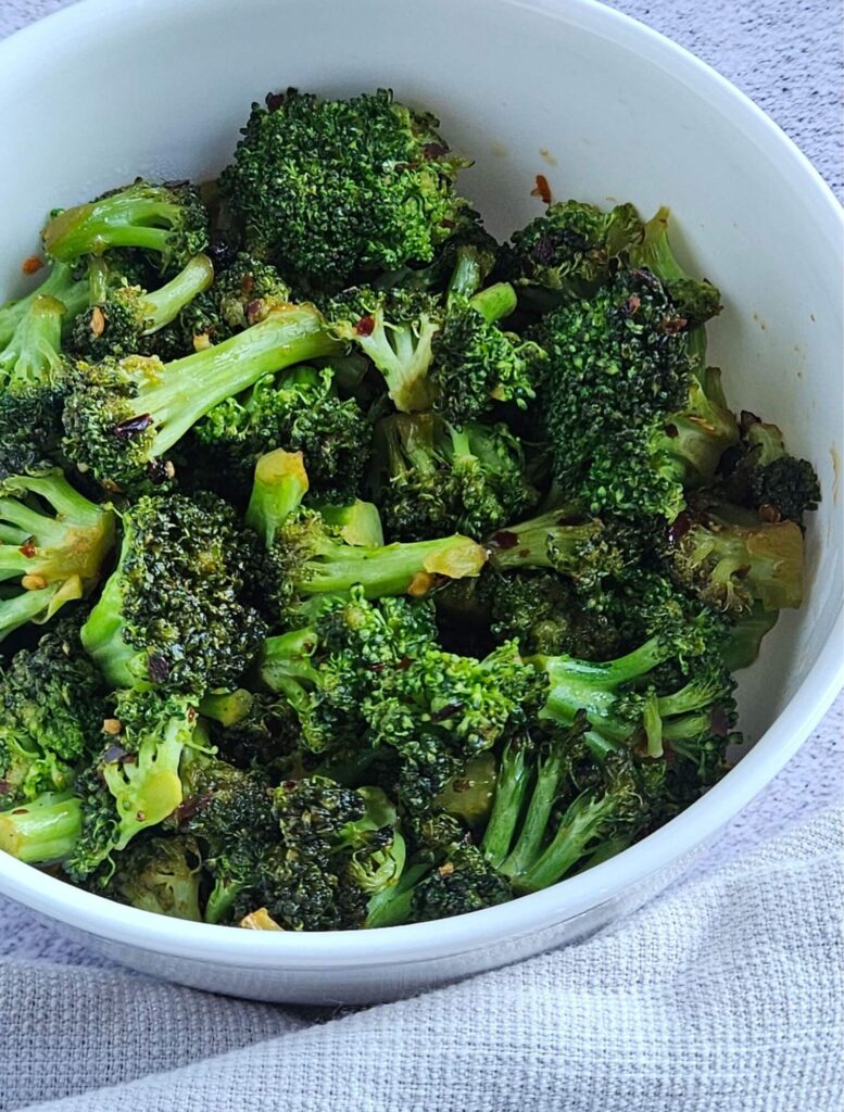 Stir fried broccoli being served in a bowl.