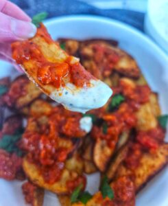 Patatas bravas with bravas sauce being dipped in garlic aioli sauce.