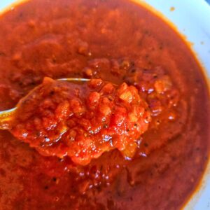 Close up image of bravas sauce being scooped with a spoon.