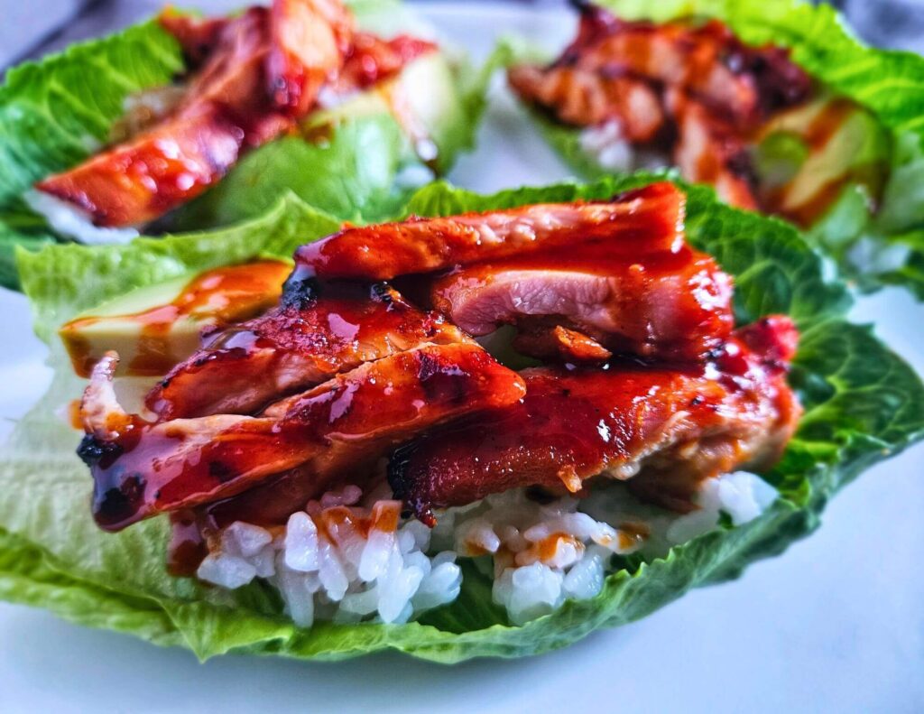 rilled Korean BBQ chicken thighs in a lettuce wrap layered with white rice, avocado and gochujang drizzle.