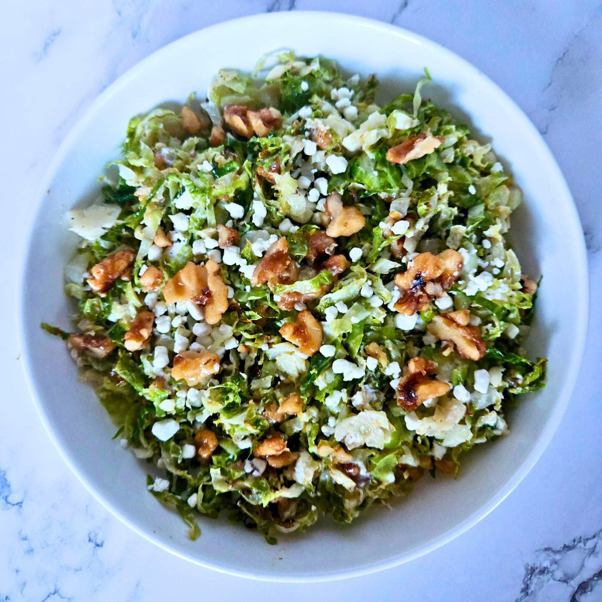 Image of roasted brussels sprouts salad with maple glazed walnuts and goat cheese crumbles. 