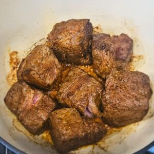 Image of chuck roast being seared in a dutch oven.