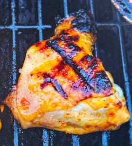 Close up image of sweet and spicy Thai chicken thighs on the grill.