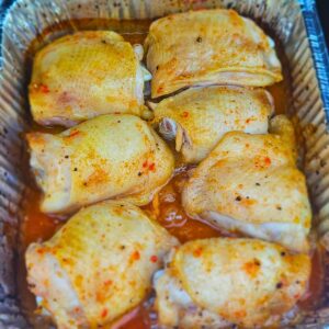 Sweet and Spicy Thai Chicken Thighs in an aluminum pan on the grill being cooked before searing.