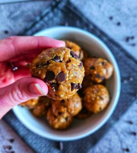 Close up image of healthy cookie dough balls being picked up from bowl.