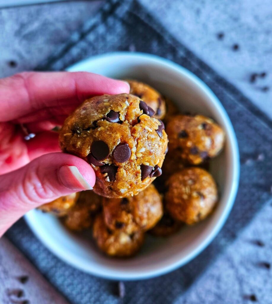 Close up image of healthy cookie dough balls being picked up from bowl.