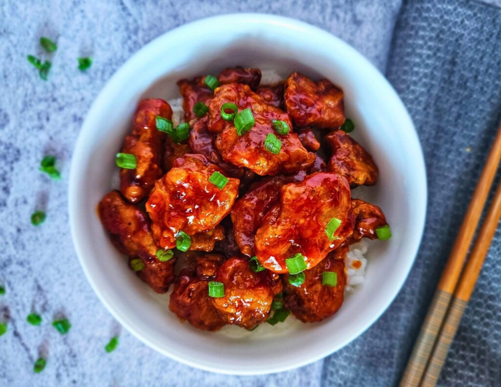 Image of Air Fryer Korean Fried Chicken being served in a bowl with chopsticks. 
