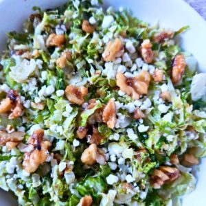 Close up image of roasted brussels sprouts salad with maple glazed walnuts, lemon dijon dressing and crumbled goat cheese.