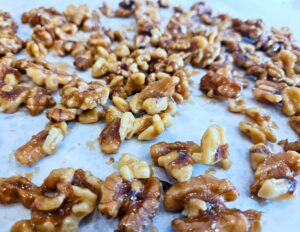 Maple glazed walnuts laying out on parchment paper to set the maple glaze.