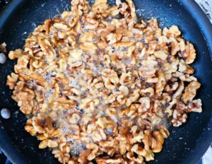 Maple glazed walnuts cooking in a pan.