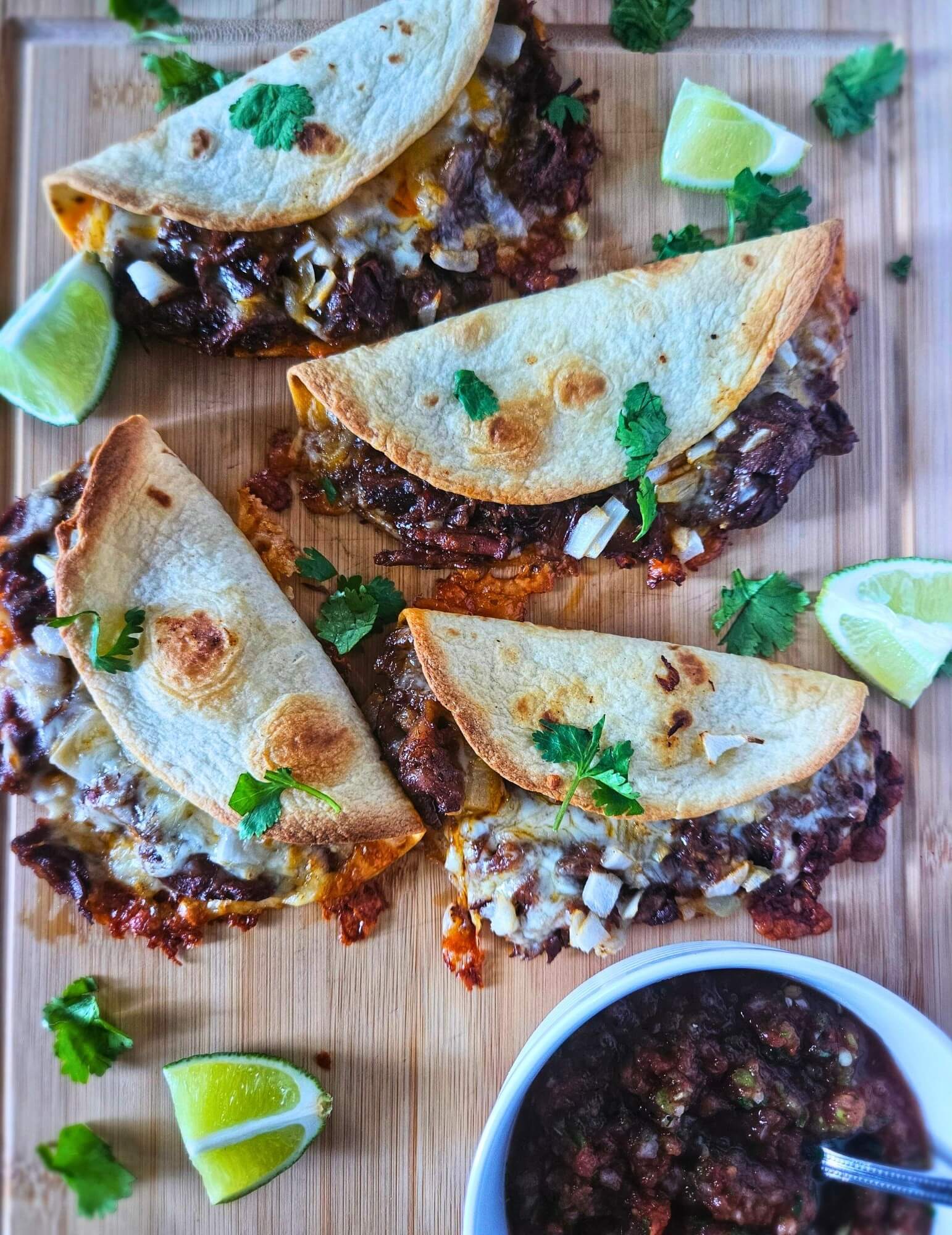 Image of crispy barbacoa tacos with slow braised beef being served with salsa and limes.