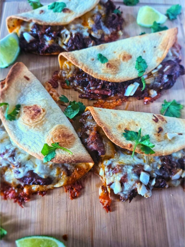 Image of crispy barbacoa tacos being served with cilantro and lime. 