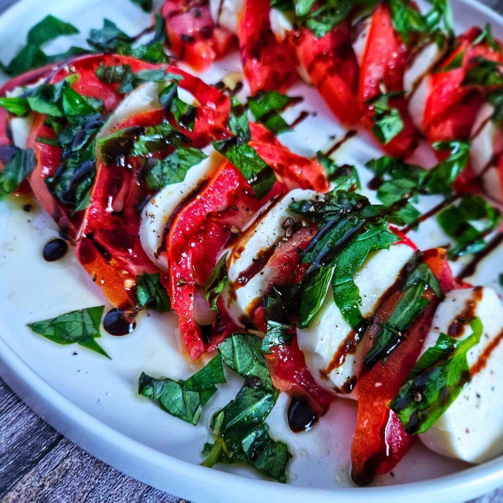 Caprese Salad 4 Close of image of caprese salad with mozzarella, tomatoes, basil and chopped balsamic drizzle.