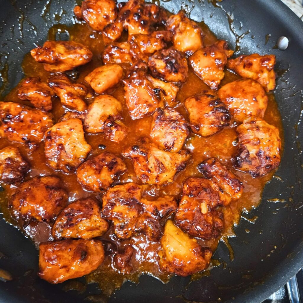 Korean Fried Chicken being tossed in the gochujang sauce.
