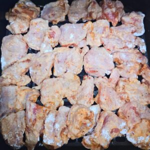 Korean Fried Chicken in the air fryer after being dipped in cornstarch.