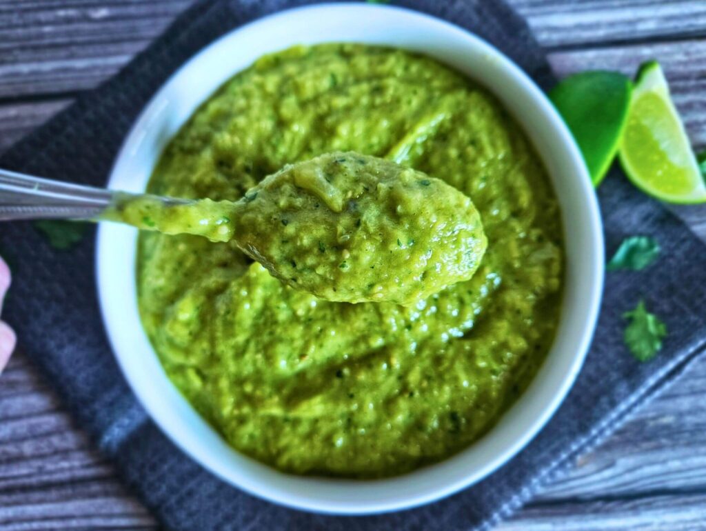 Tomatillo Avocado Salsa 5 Tomatillo avocado salsa in a serving bowl being scooped with a spoon.