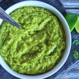 Image of easy tomatillo avocado salsa in a serving bowl with a spoon.