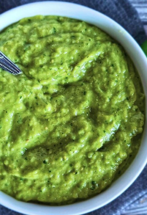 Image of easy tomatillo avocado salsa in a serving bowl with a spoon.