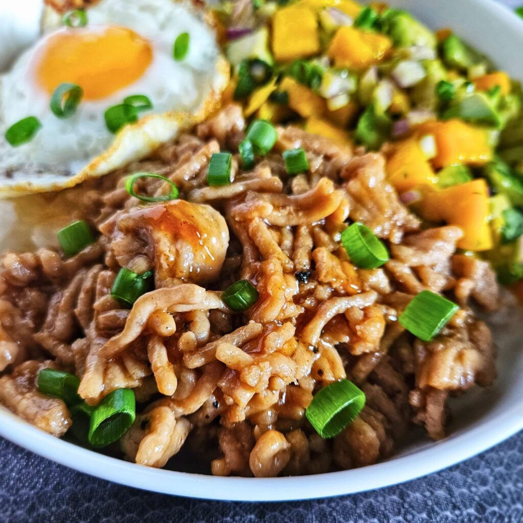 teriyaki chicken bowl 13 Image of teriyaki chicken rice bowl with avocado mango salsa over white rice and a fried egg.
