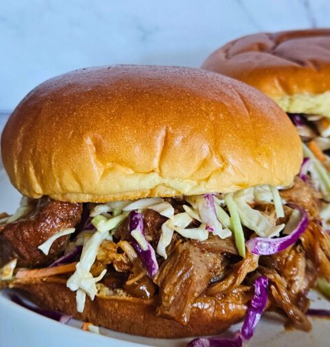 Image of Dutch oven pulled pork braised in apple cider made into a pulled pork sandwich with creamy coleslaw.