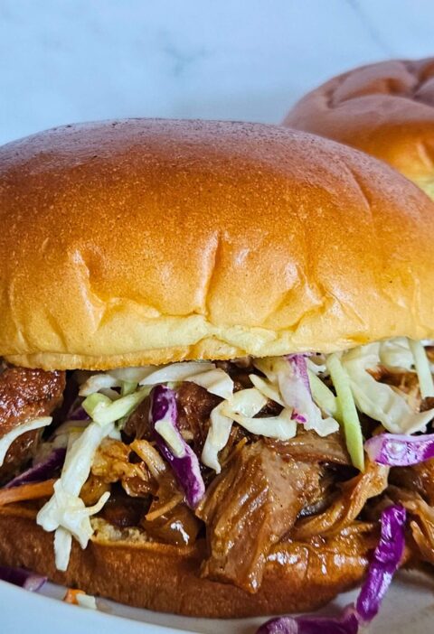 Image of Dutch oven pulled pork braised in apple cider made into a pulled pork sandwich with creamy coleslaw.