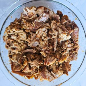 Pork being shredded into pulled pork.