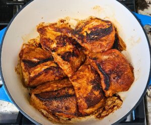 Seasoned pork pieces being seared in the Dutch oven.