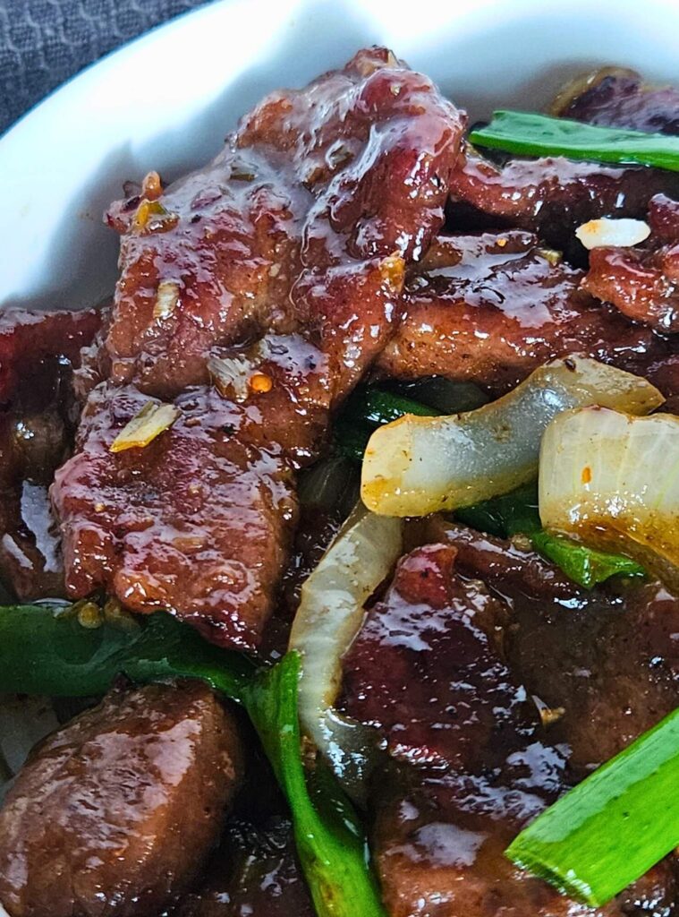 Close up image of 
Mongolian beef stir fry being served over white rice.