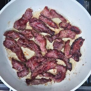 Flank steak being seared in a skillet for the Mongolian beef stir fry recipe.