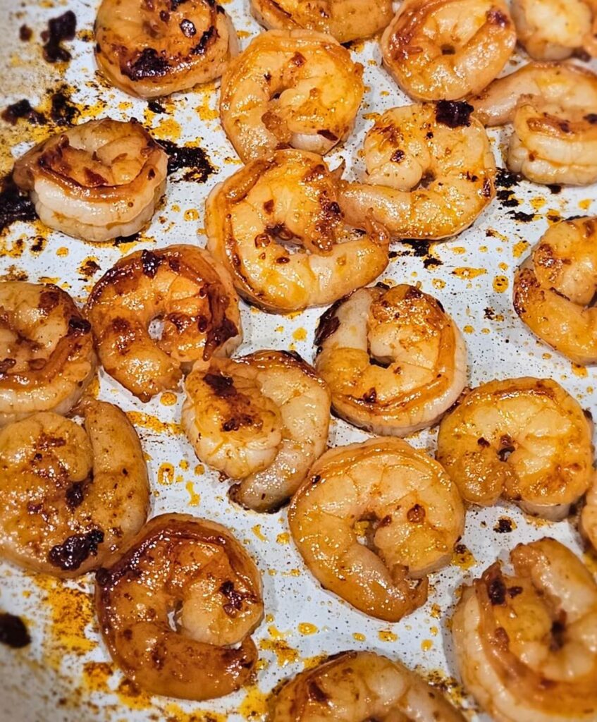Chili shrimp being seared in a skillet for the peanut noodle bowl.