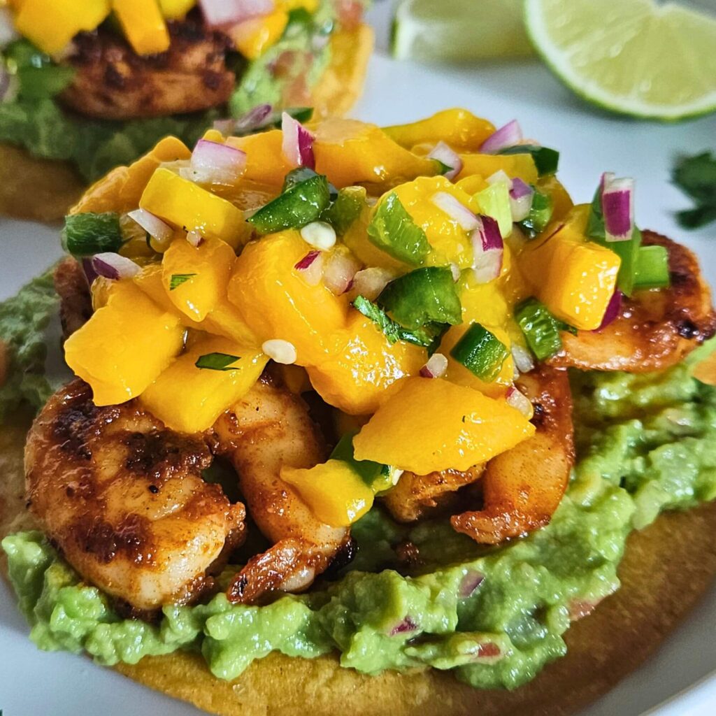 Shrimp tostadas with a homemade tostada layered with guacamole, blackened shrimp and mango salsa.