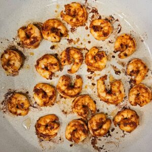 Blackened shrimp being cooked in a skillet.