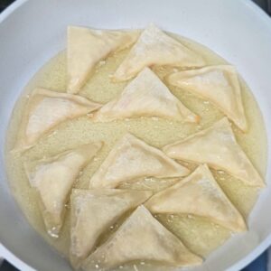 Picture showing how to make crab rangoons by shallow frying them on each side.