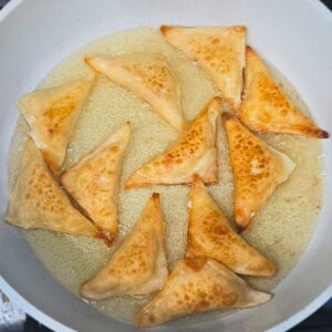 Picture showing how to make crab rangoons by shallow frying them on each side.