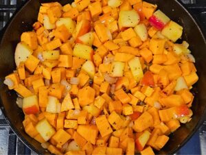 Sautéing sweet potatoes and apples in cast iron skillet.