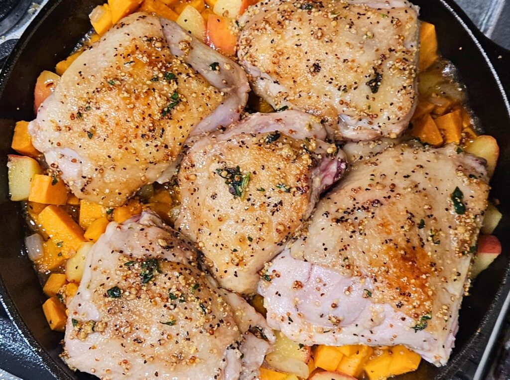 Apple Cider Chicken Prep 8 Apple cider glazed chicken thighs in cast iron skillet over sweet potatoes before baking.