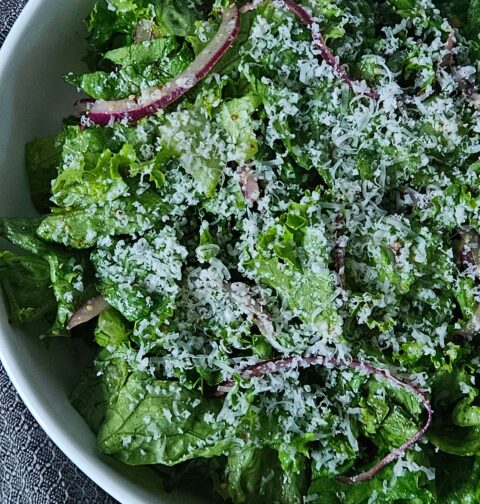 Close up image of parmesan chipped salad with red onion and lemon dijon dressing.