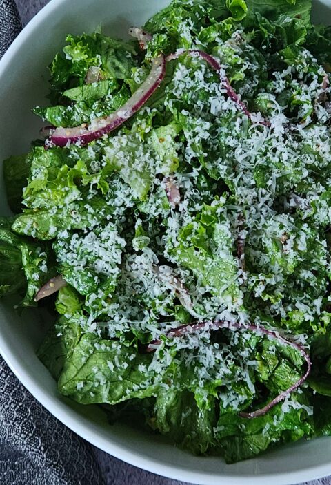 Close up image of parmesan chipped salad with red onion and lemon dijon dressing.