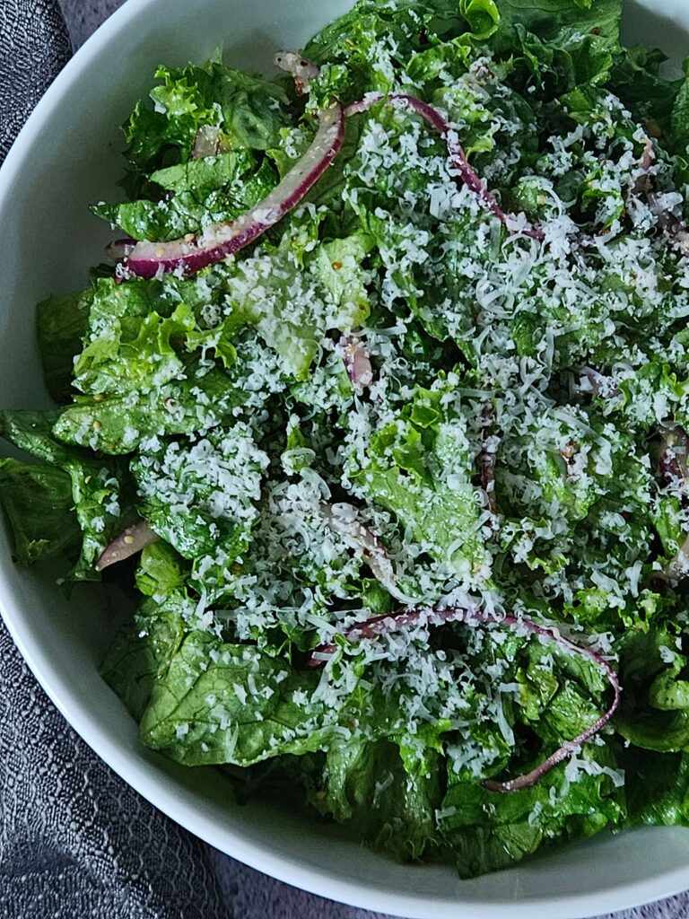 Parmesan Chopped Salad 16 Close up image of parmesan chipped salad with red onion and lemon dijon dressing.