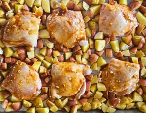 Sheen pan honey mustard chicken thighs with potatoes before roasting.