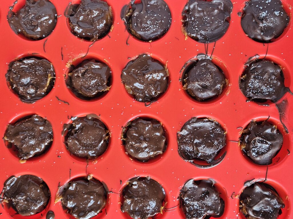 Dark chocolate covered pumpkin caramel bites in silicone muffin pan.