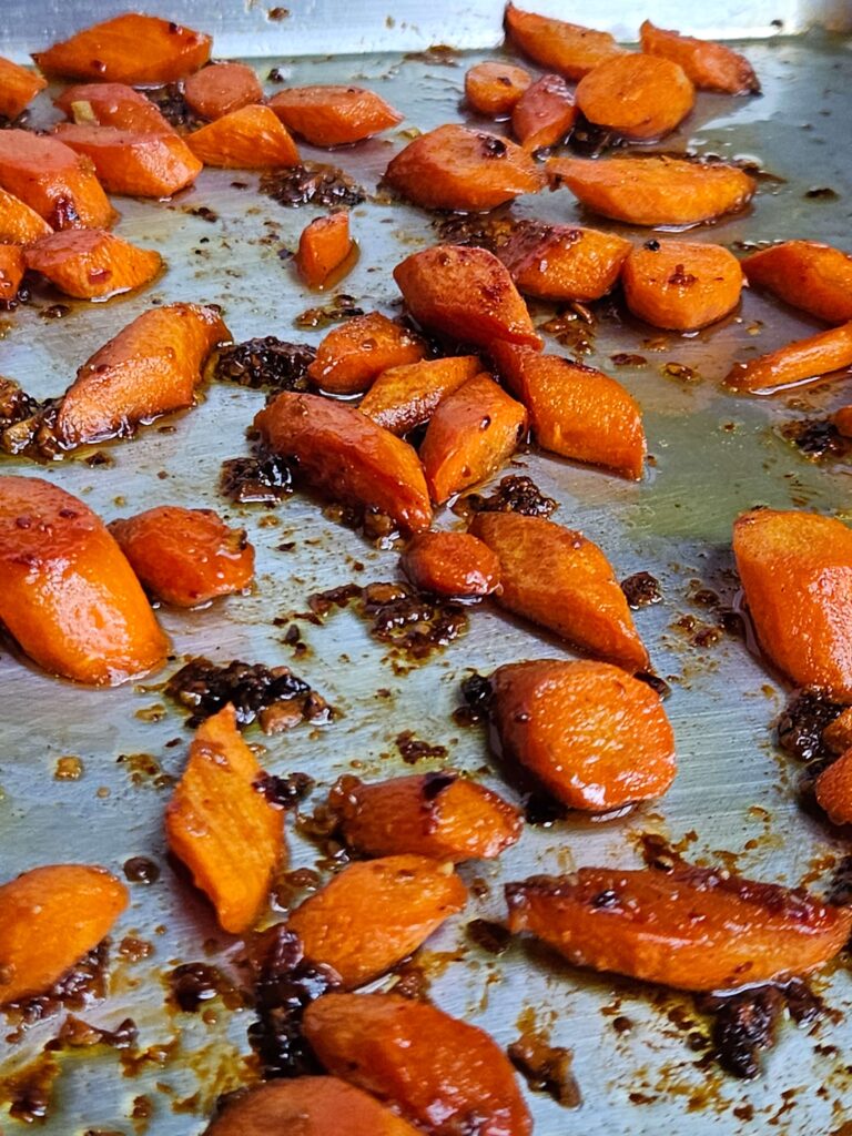 Image of honey glazed carrots after being roasted on a baking sheet.