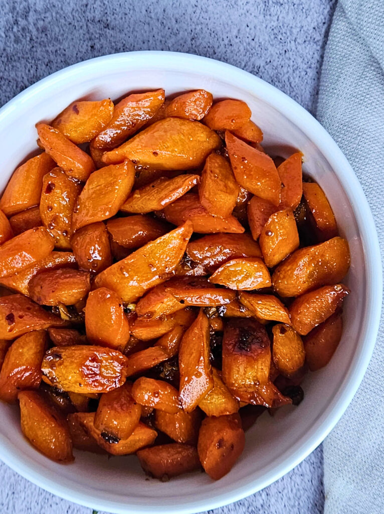 Image of honey glazed carrots being served in a white bowl.