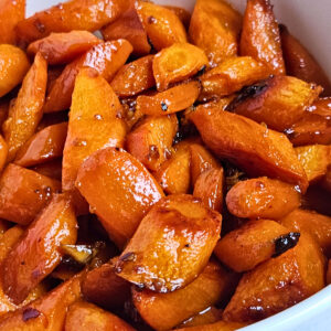 Close up image of honey glazed carrots being served in a white bowl.