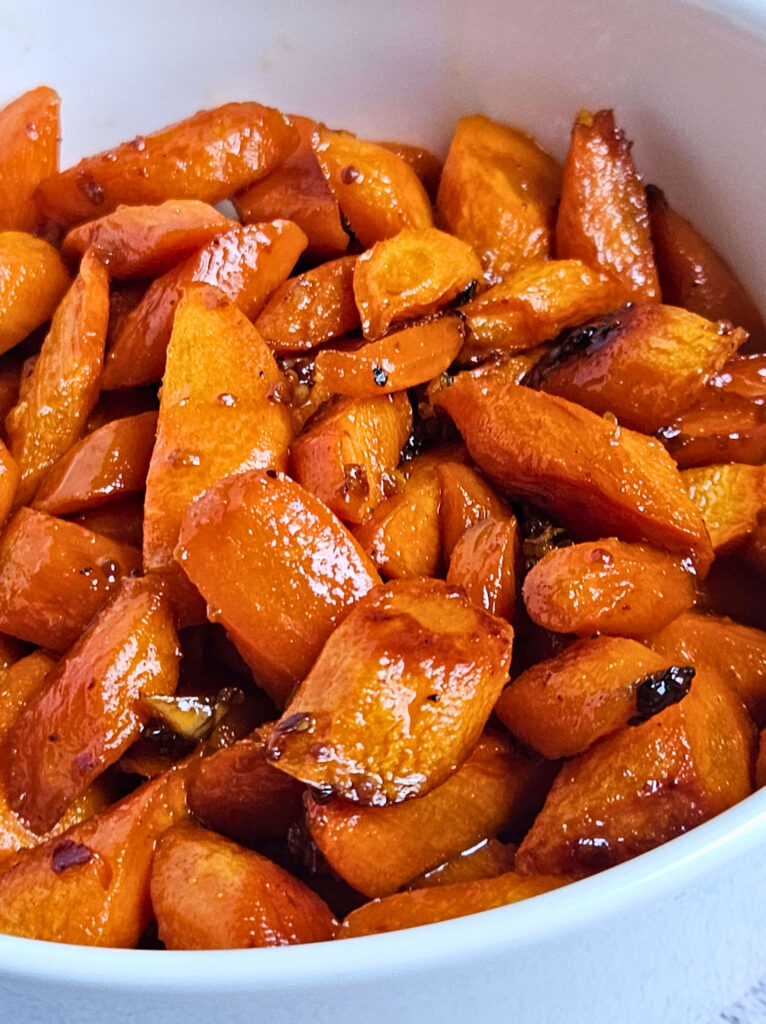 Close up image of honey glazed carrots being served in a white bowl.