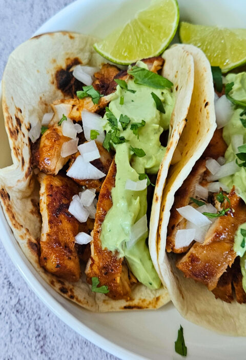 Close up image of chipotle chicken tacos with avocado crema.