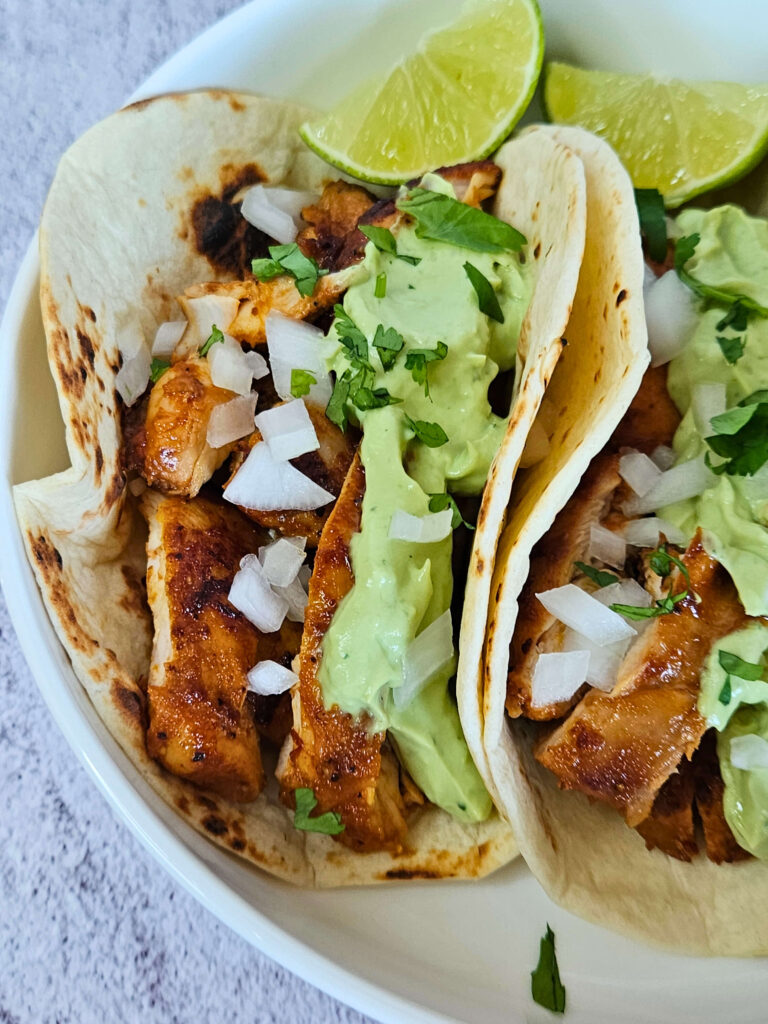 Close up image of chipotle chicken tacos with avocado crema.