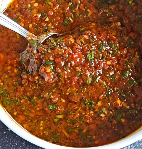 Image of red chimichurri being served in a white bowl.