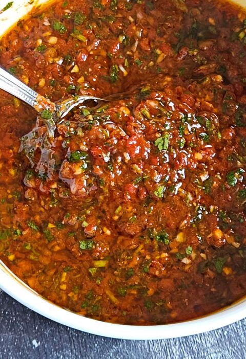 Image of red chimichurri being served in a white bowl.