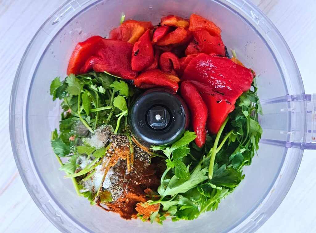 Red chimichurri ingredients in food processor before blending.